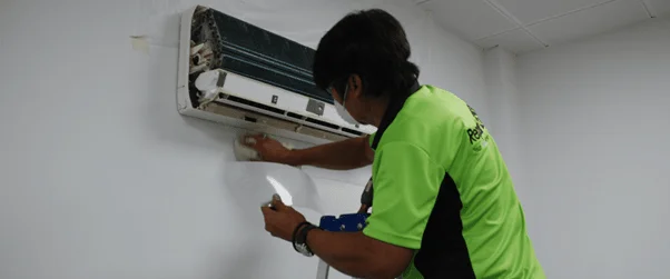 A professional technician servicing an air conditioning unit in Dubai. The expert is wearing a uniform and using specialized tools to maintain the AC system, ensuring optimal performance and efficiency. The background includes a well-maintained indoor environment, reflecting the quality of AC services in Dubai.